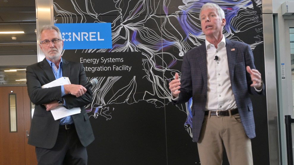 Two white men in suits stand in front of a sign that says NREL.