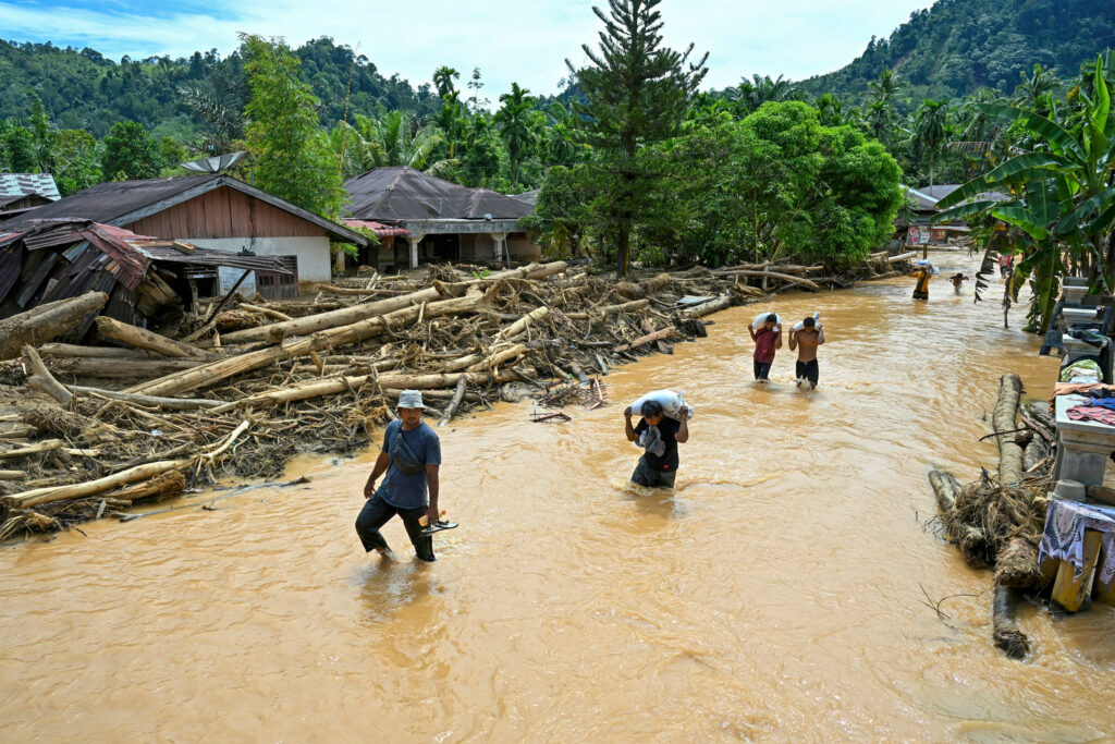 People wade through floodwater in the aftermath of flash floods on Dec. 2 in Central Tapanuli, North Sumatra. Credit: Yt Hariono/AFP via Getty Images