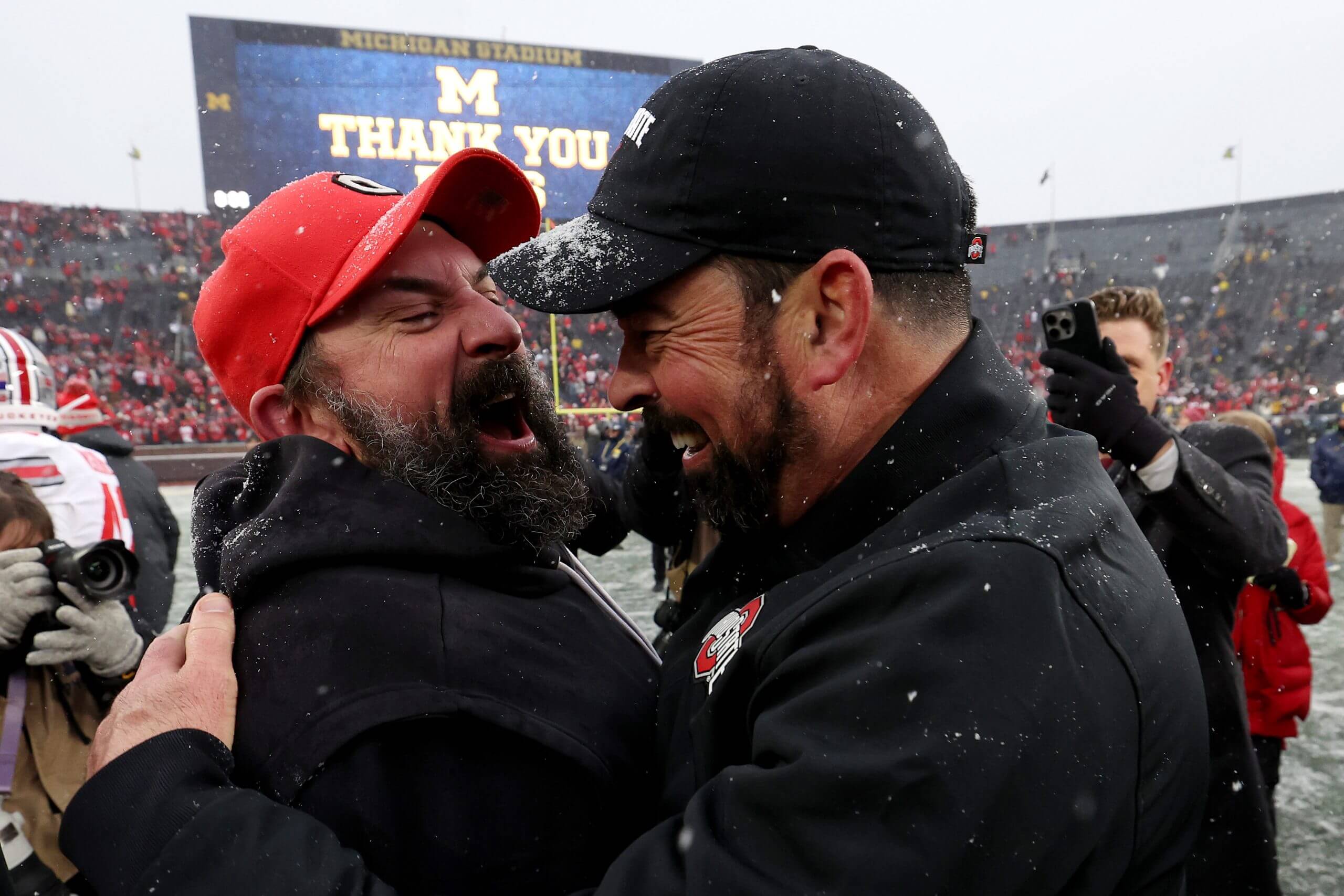 Ohio State defensive coordinator Matt Patricia and coach Ryan Day embrace and celebrate on the field after beating Michigan