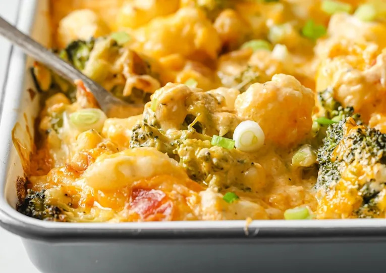 Loaded broccoli cauliflower casserole in a baking dish garnished with green onions.