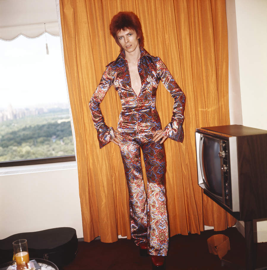 Rock and roll musician David Bowie poses for a portrait dressed as Ziggy Stardust in a hotel room in 1973 in New York City, New York