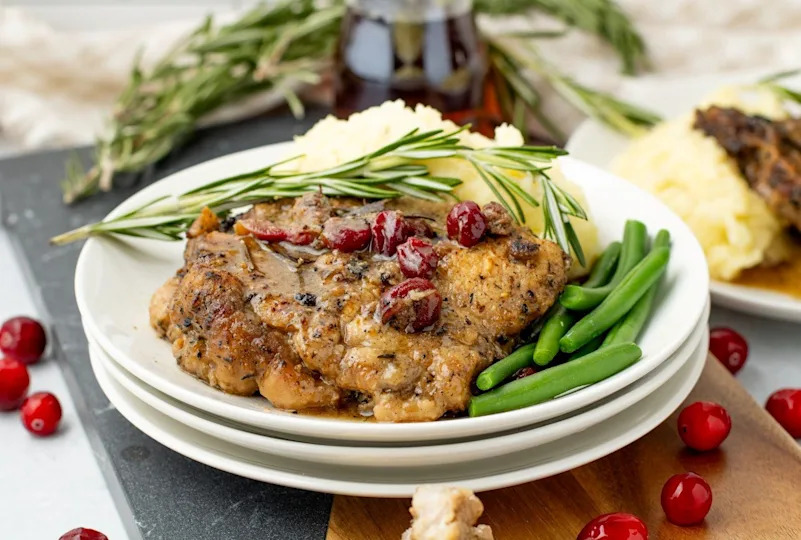 Maple cranberry pork chop served with mashed potatoes and green beans.