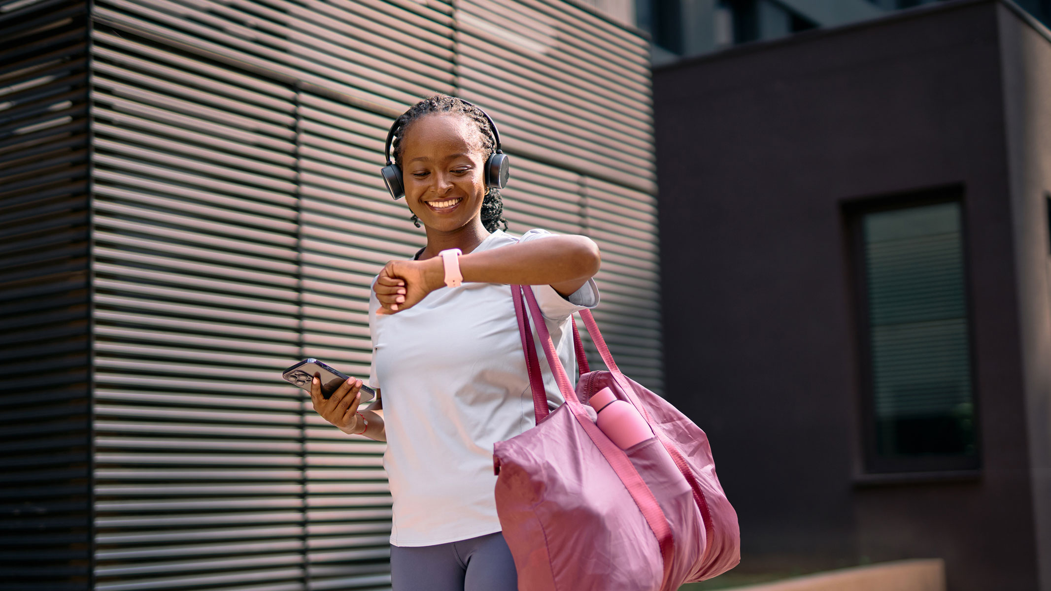 A picture of a young woman smiling while looking at her smartwatch