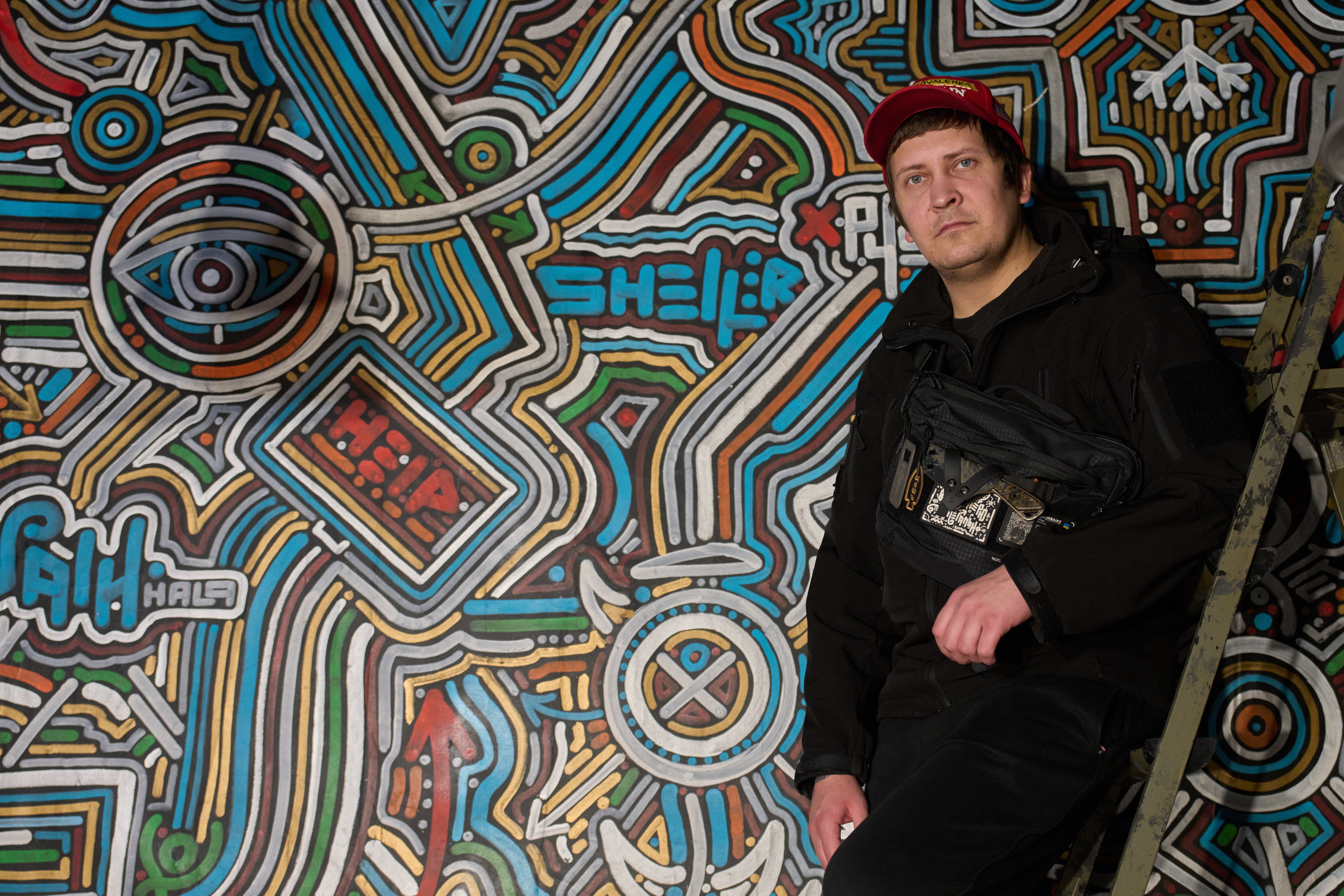 Ukrainian street artist Maxim Kilderov stands by his painting containing symbols and messages of resistance