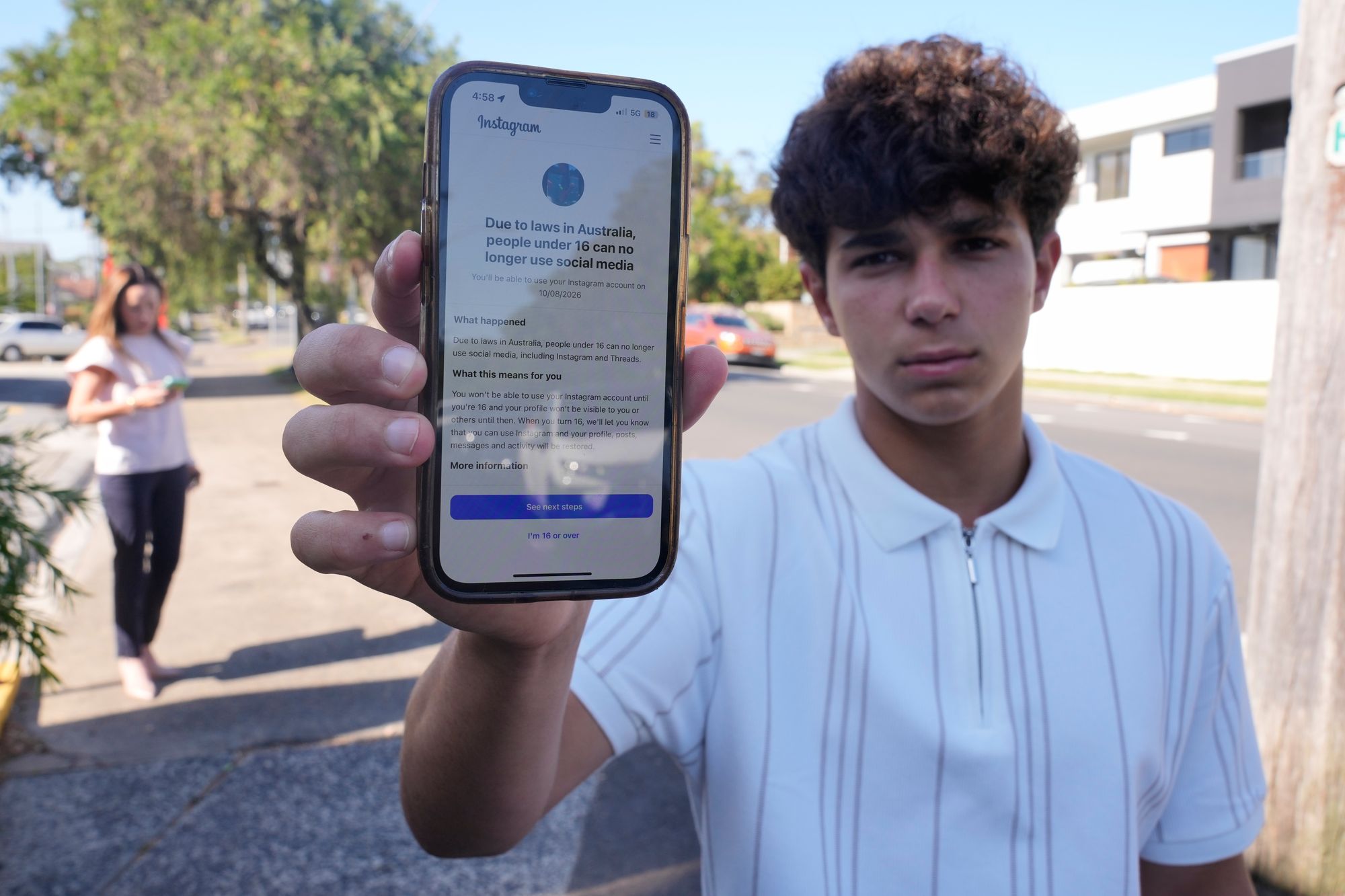 Noah Jones shows a warning on his phone that says he cannot access a social media site in Sydney (AP Photo/Rick Rycroft)
