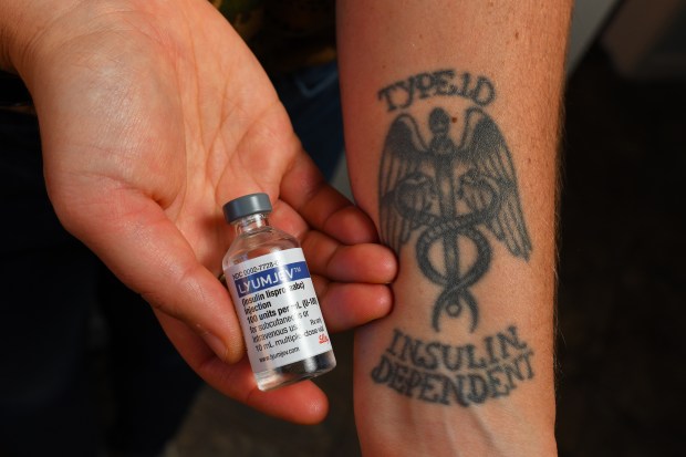 Emma Kleck, of Santa Cruz, holds a vial of insulin next to her tattoo while at her home in Santa Cruz, Calif., on Friday, Dec.12, 2025. Kleck has type I diabetes since 2001. California is getting into the insulin business. In January, the state will begin selling a long-acting insulin for diabetes patients at $55 for roughly a month's supply. (Jose Carlos Fajardo/Bay Area News Group)