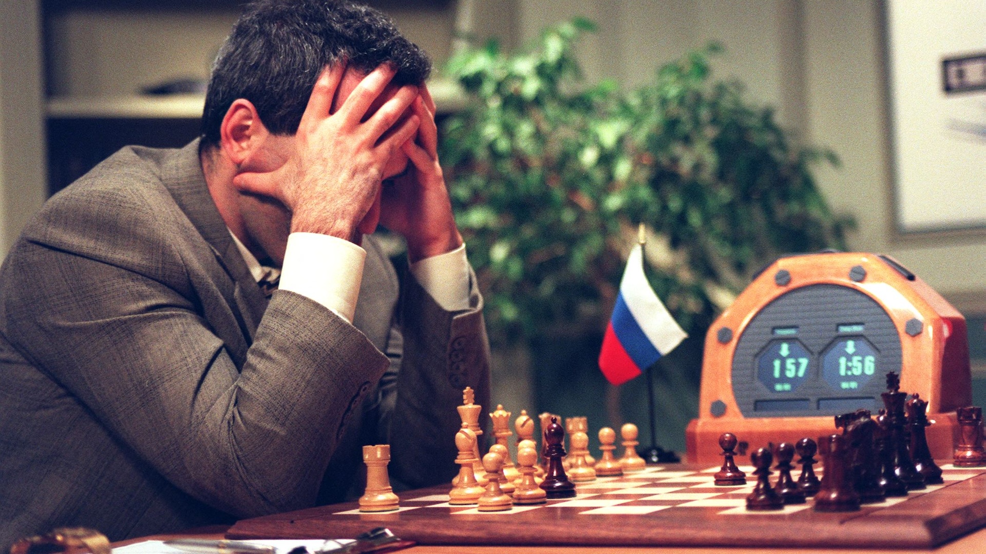 a man holds his head in his hands as he looks at a chess board