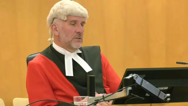Judge Andrew Menary reading his sentencing remarks in court, in a red gown and white wig.