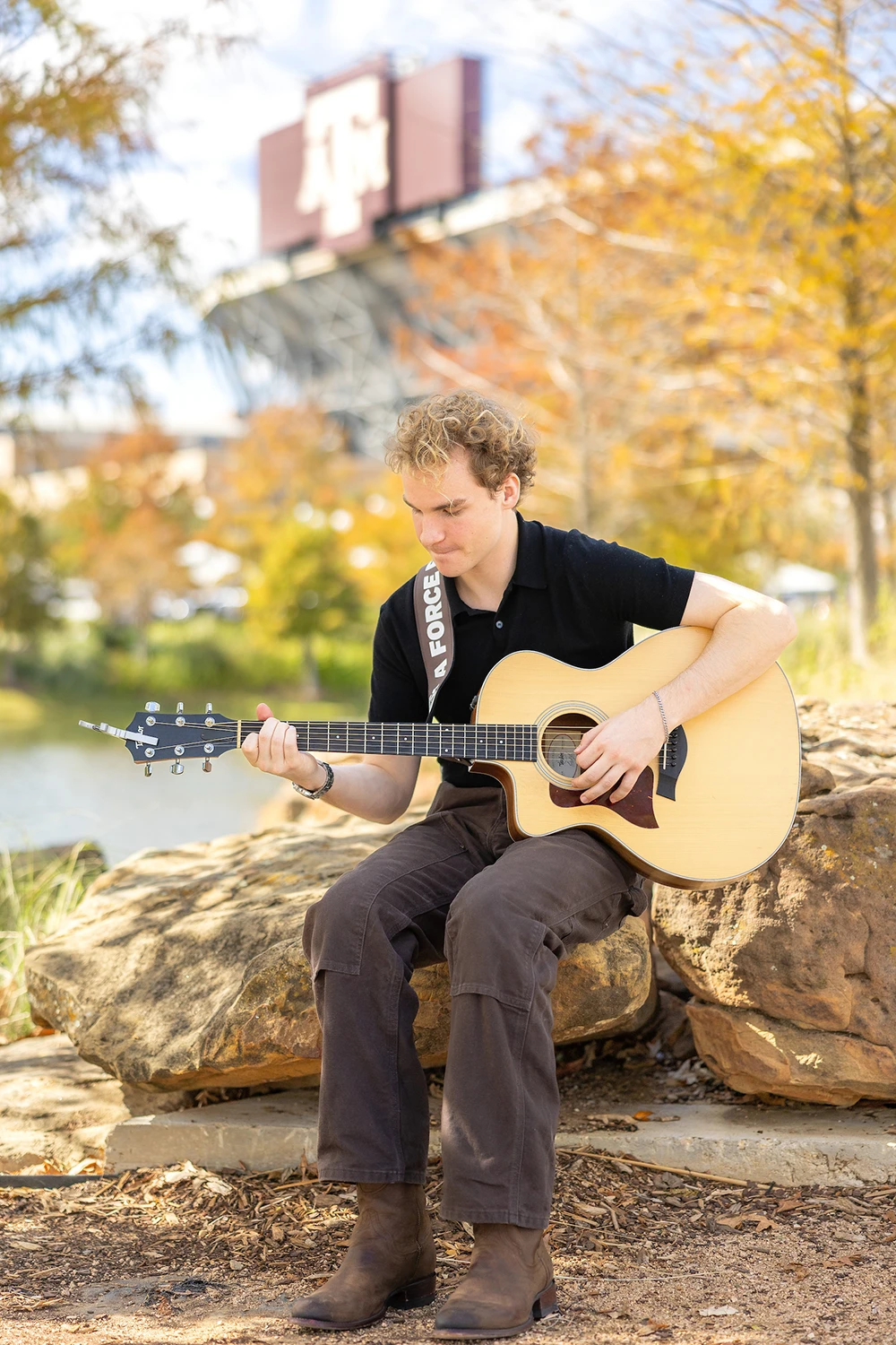 Portrait of Aiden Ross playing his acoustic guitar in Aggie Park