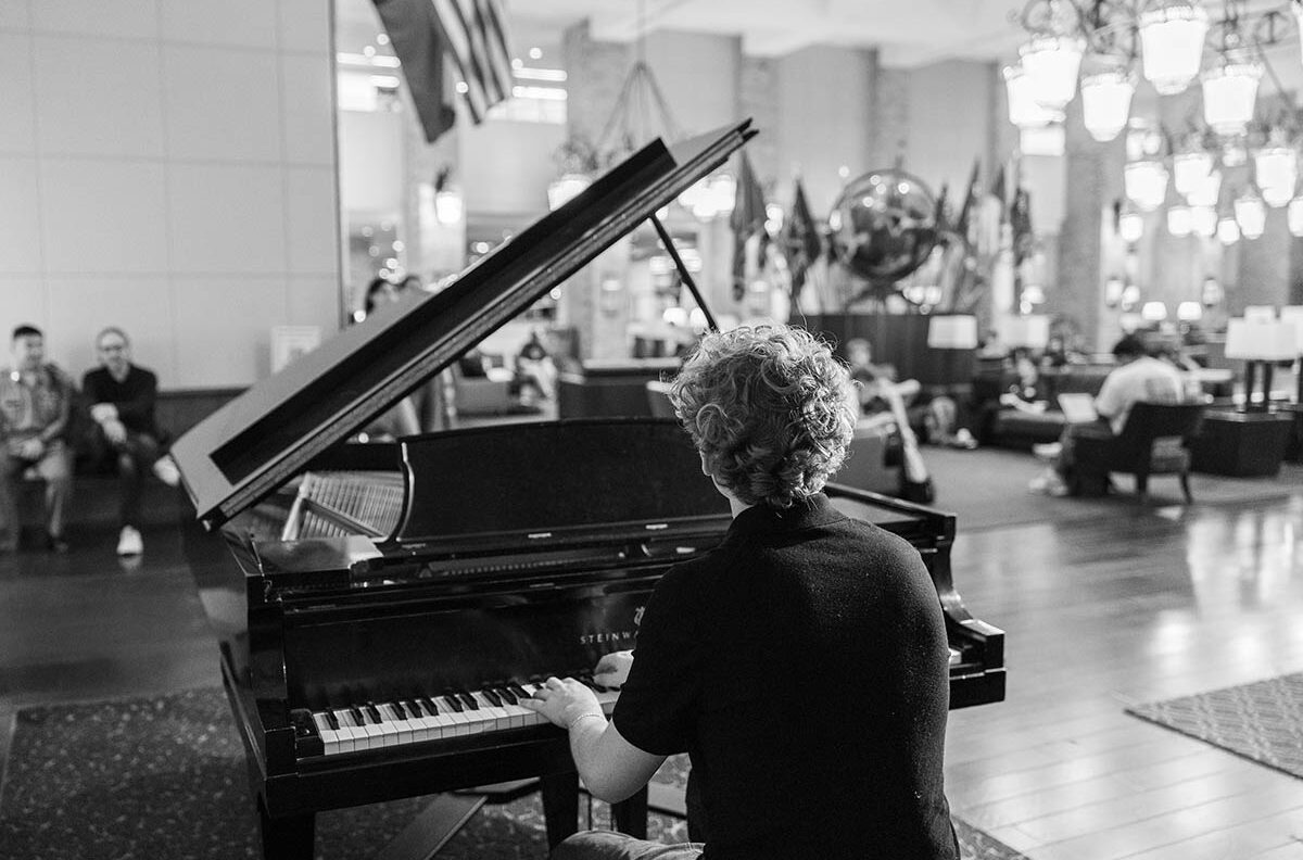 Aiden Ross playing a piano in the Texas A&M Memorial Student Center flag room