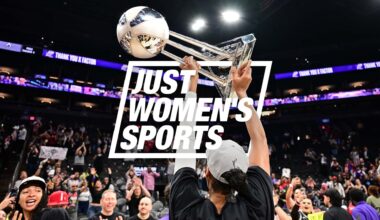 A'ja Wilson holds up the WNBA Championship trophy in front of a crowded stadium.
