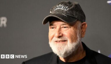 Hollywood actor and director Rob Reiner wearing a black cap and black jacket.