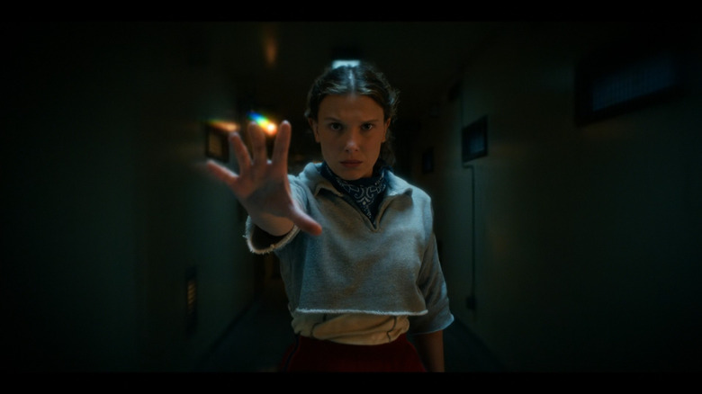 Eleven (Millie Bobby Brown) raising her hand in Stranger Things