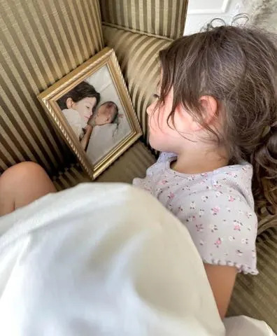 Melissa Mae Carlton/Instagram Melissa Mae Carlton's daughter Molly looking at a photo of herself and her late older sister, Abigail