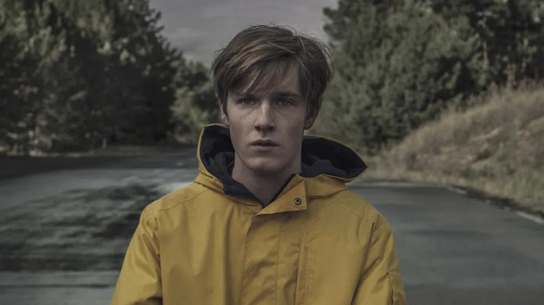 Jonas Kahnwald (Louis Hofman) stands in middle of a rainy, overcast street on Dark