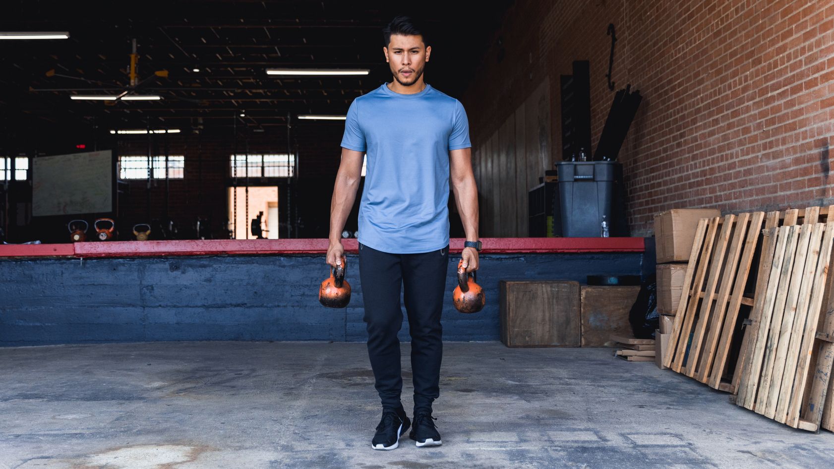 Man in warehouse gym carrying kettlebells