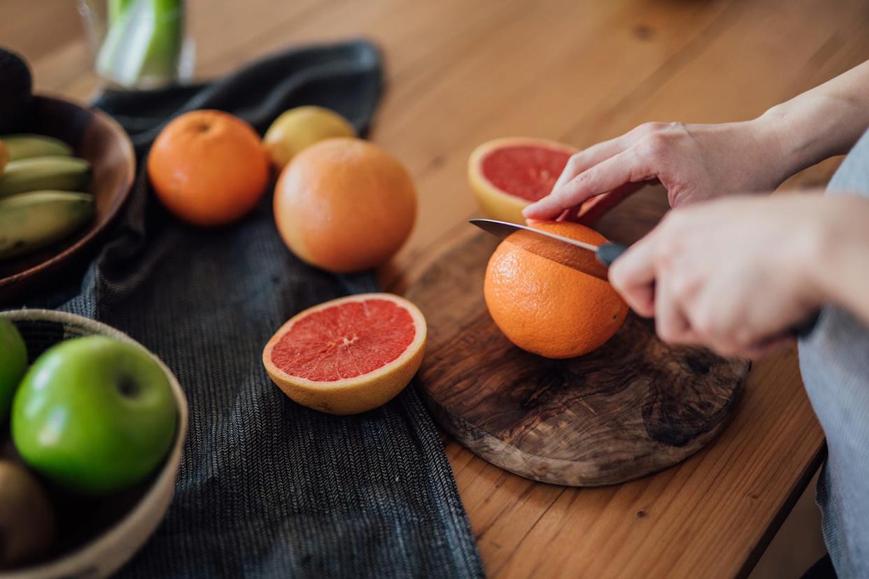 woman's hands chopping oranges and grapefruits