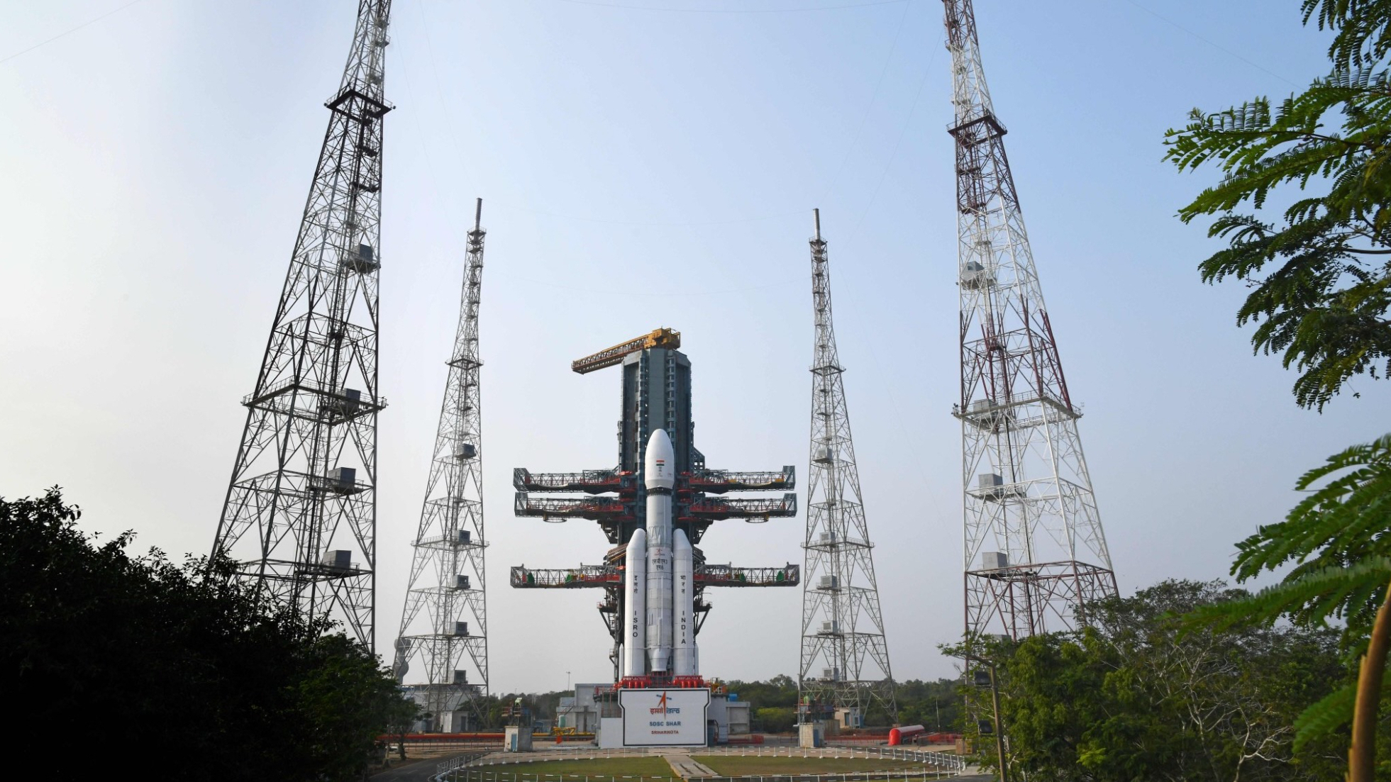 a white rocket stands on a launch pad beneath a cloudy sky