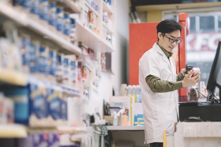 A male pharmacist scanning a pharmacy product for his customer.