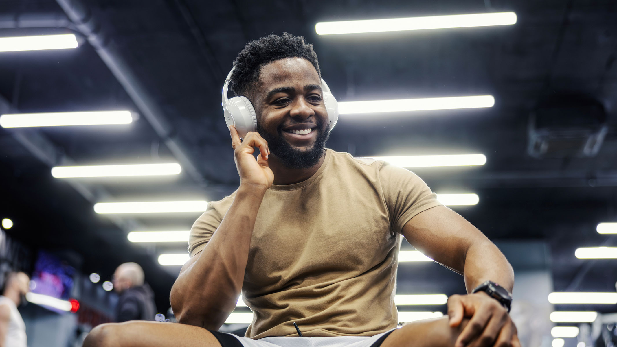 A picture of a young man listening to his headphones in the gym