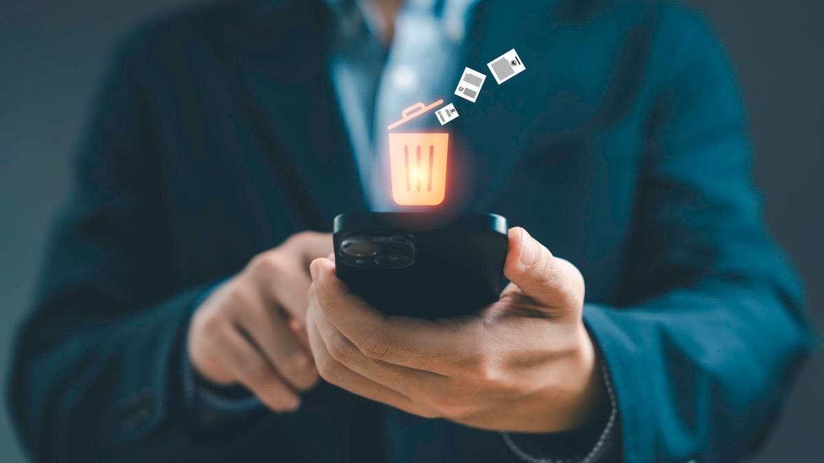 A person holds out a phone with an illustration of a filling trash can above it.