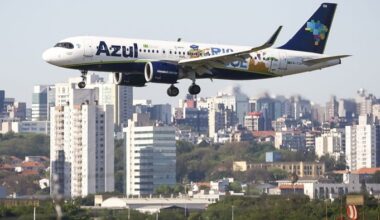 Azul Airbus A320 lands at Salgado Filho airport with city buildings in the background, marking the airport’s reopening after flood repairs.