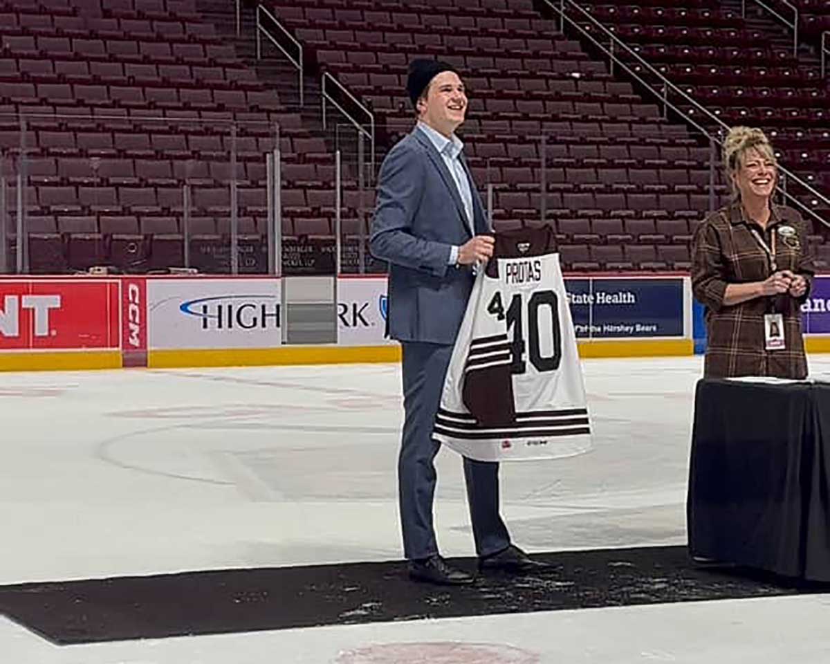 Ilya Protas holds up a jersey for auction