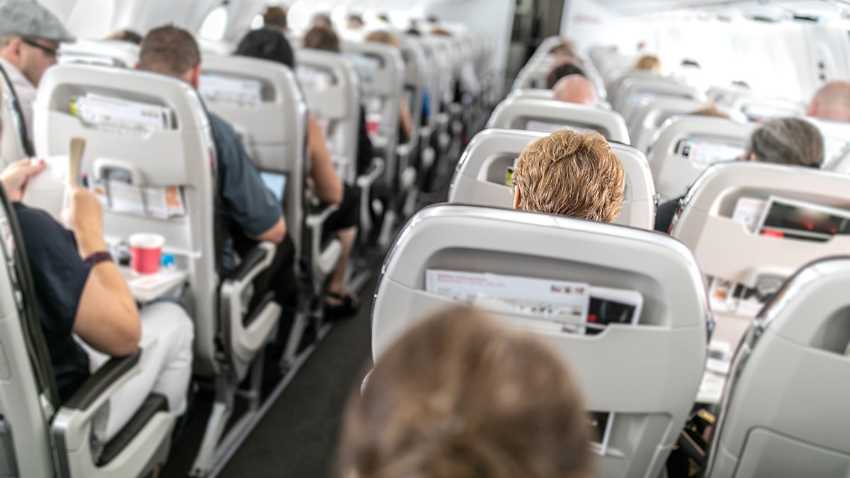 Interior of commercial airplane with passengers in their seats during flight.