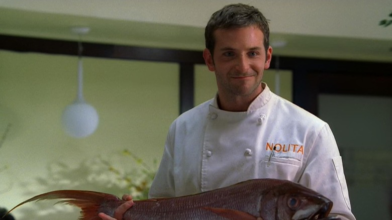 Jack Bourdain (Bradley Cooper) holding a fish in the Nolita restaurant in 