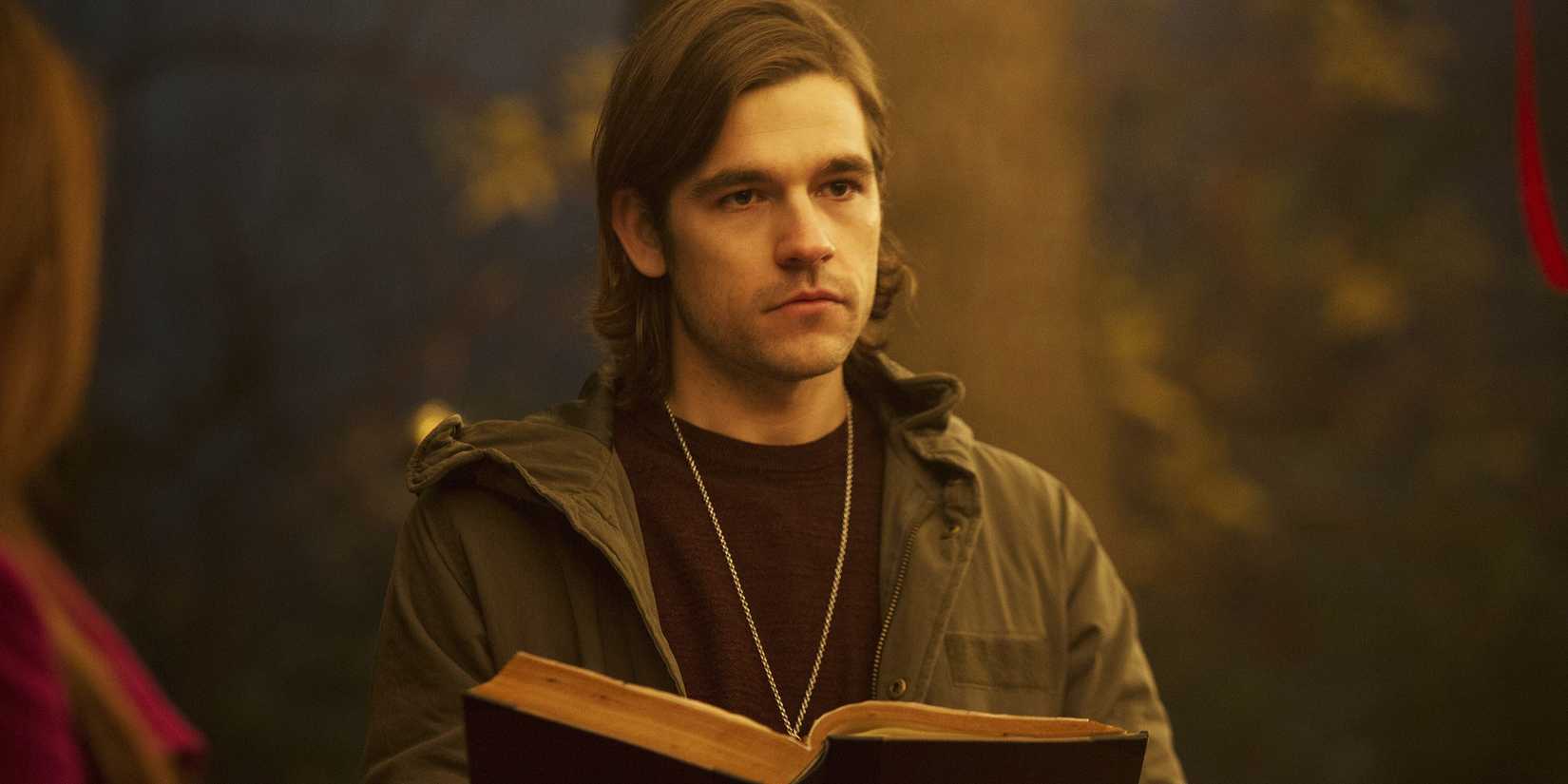 Jason Ralph as Quentin Coldwater holding a book in The Magicians