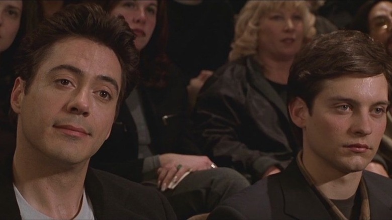 Robert Downey Jr. as Terry Crabtree sits next to Tobey Maguire as James Leer in a lecture hall in Wonder Boys