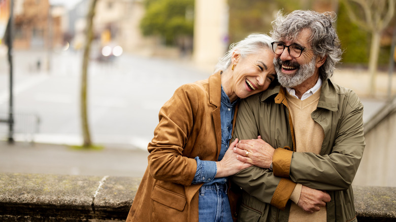 Happy middle-agedd couple in jackets, standing outside
