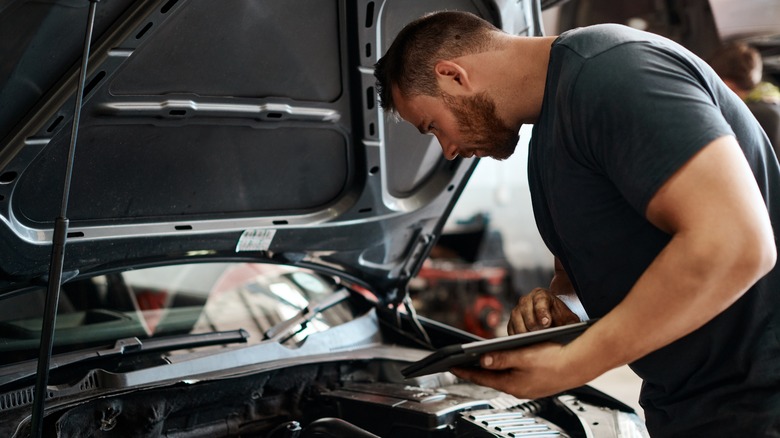 A man doing repairs on the engine block of a car