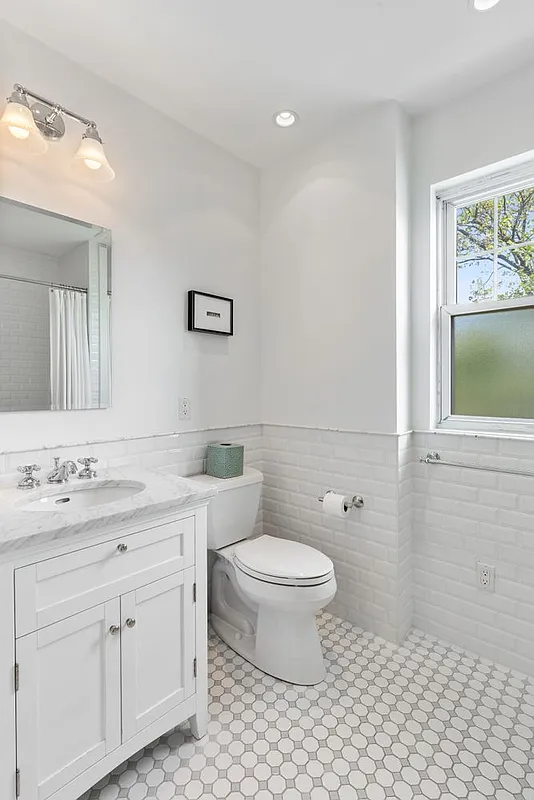 bathroom with white fixtures, white tile on walls