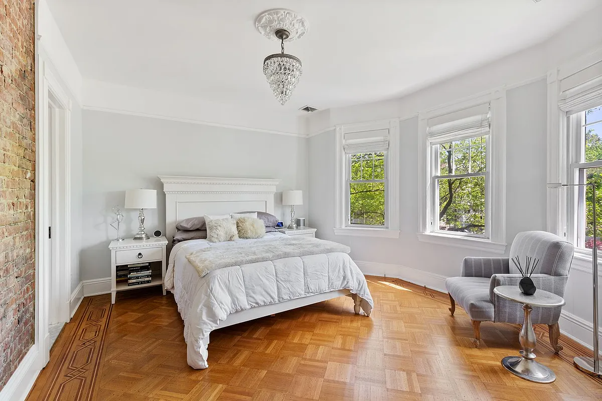 bedroom with wood floor, exposed brick on one wall