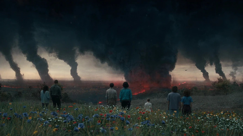 Several people watching black smoke emanating from a red chasm on the ground on Stranger Things