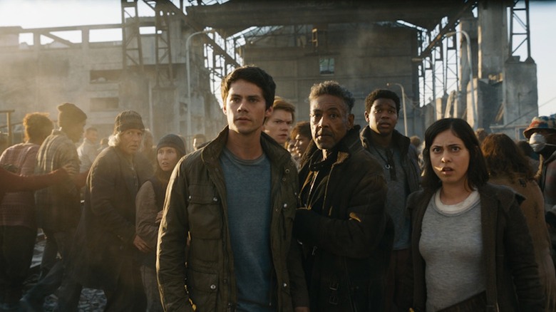 Dylan O'Brien as Thomas, Giancarlo Esposito as Jorge, and Rosa Salazar as Brenda stand outside a factory in Maze Runner: The Death Cure