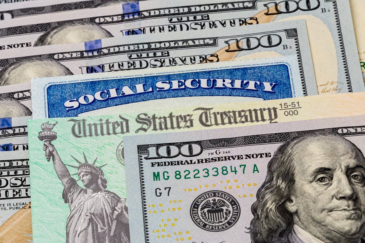 A Social Security card and check from the U.S. Treasury sandwiched between $100 bills.