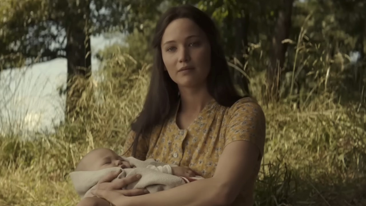 Jennifer Lawrence's Katniss Everdeen holding a baby while outdoors at the end of Hunger Games: Mockingjay Part 2