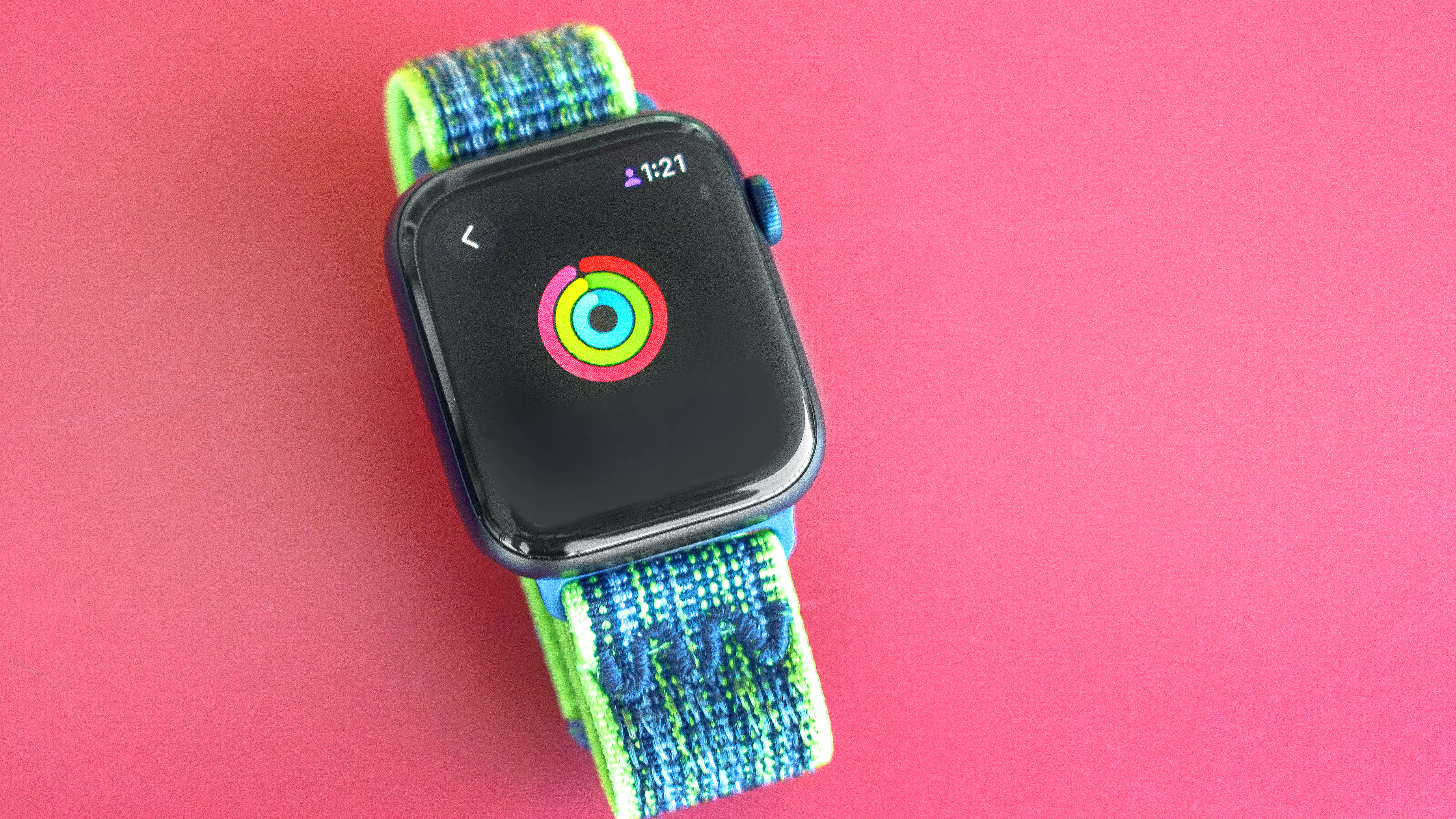 Apple Watch SE sitting on a red table with the owner's Activity Rings shown nearly closed