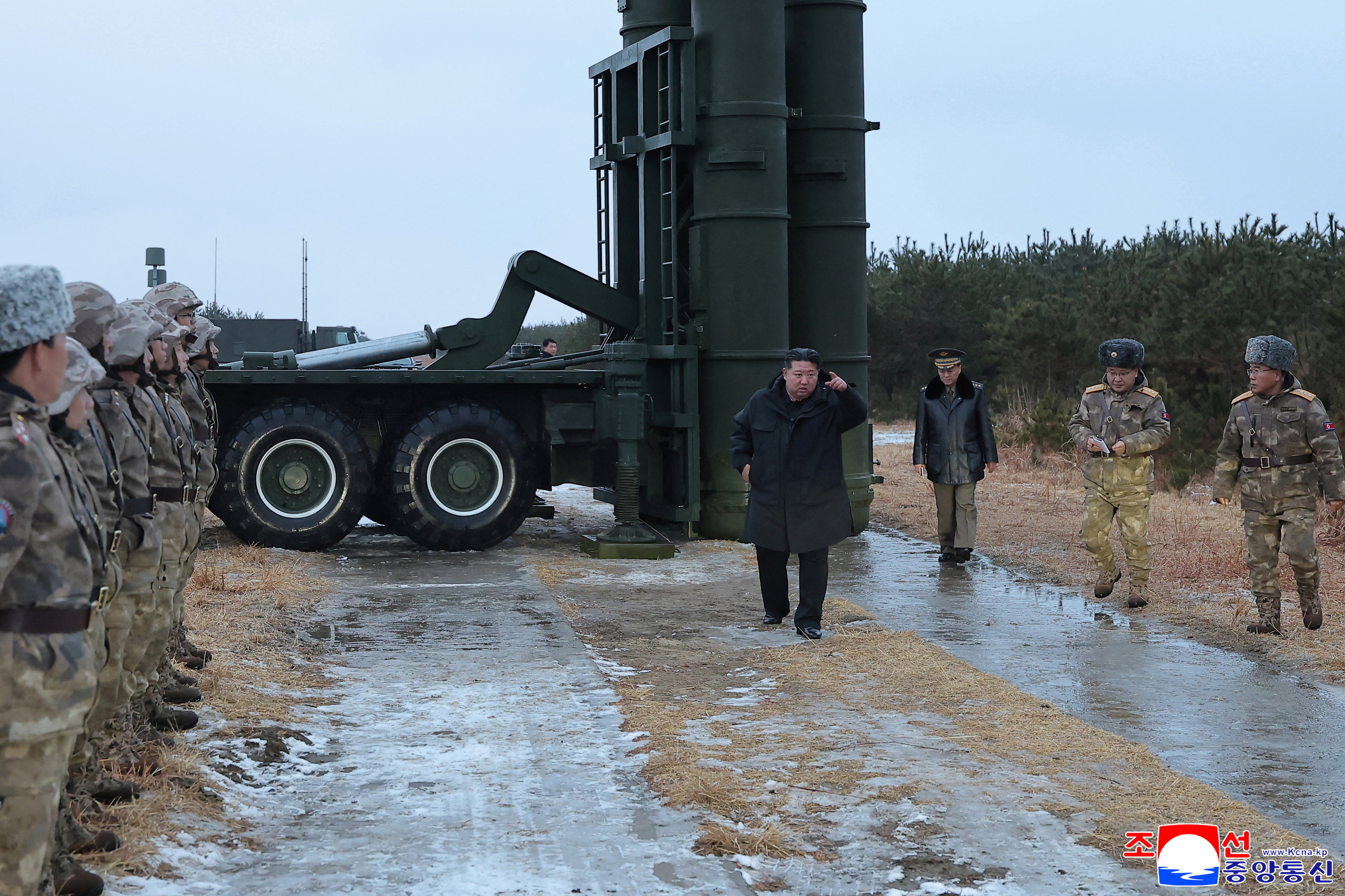 North Korean leader Kim Jong Un walks past soldiers and a long-range surface-to-air missile launcher.