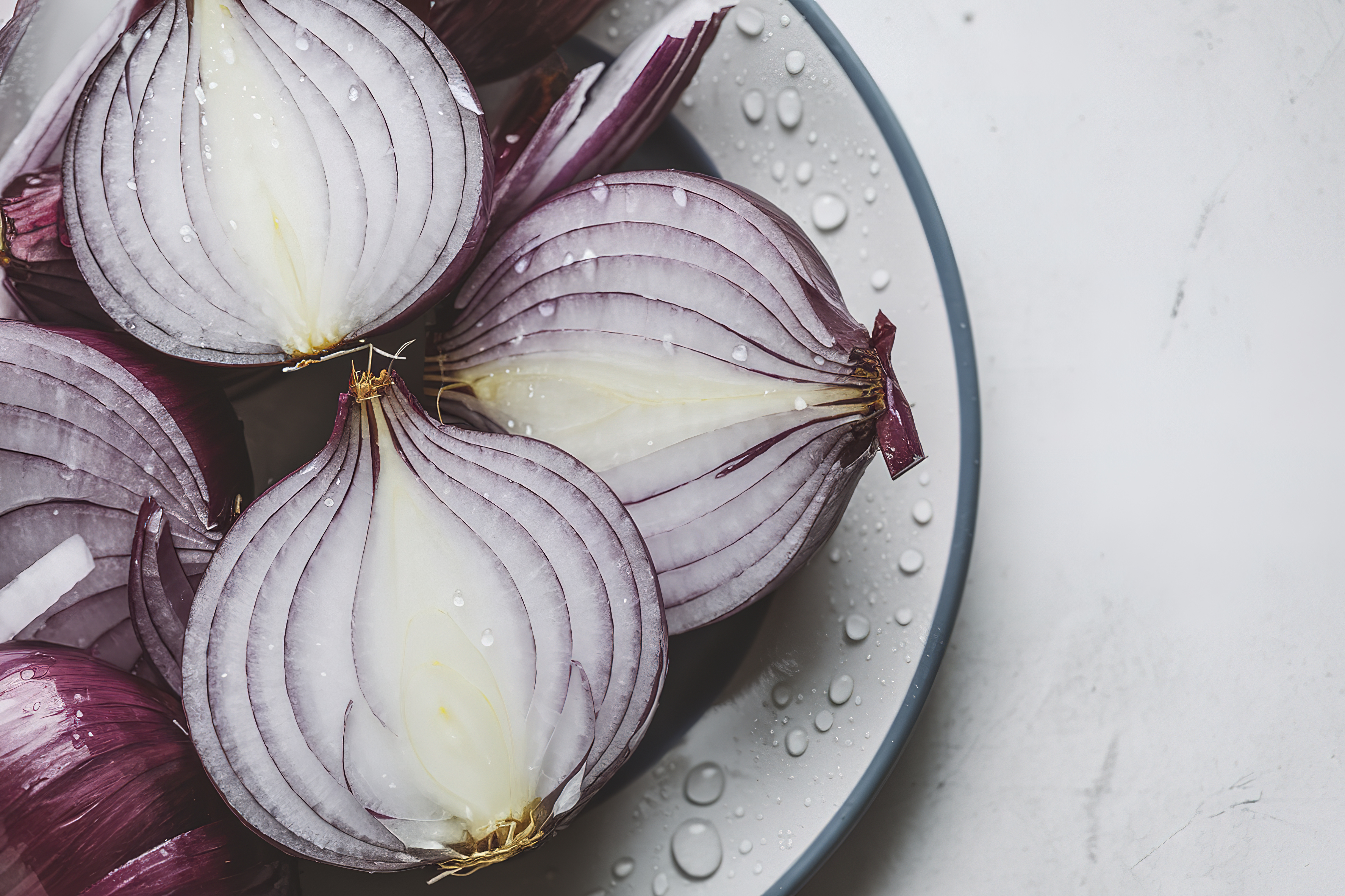Sliced red onions with water droplets on a white background.
