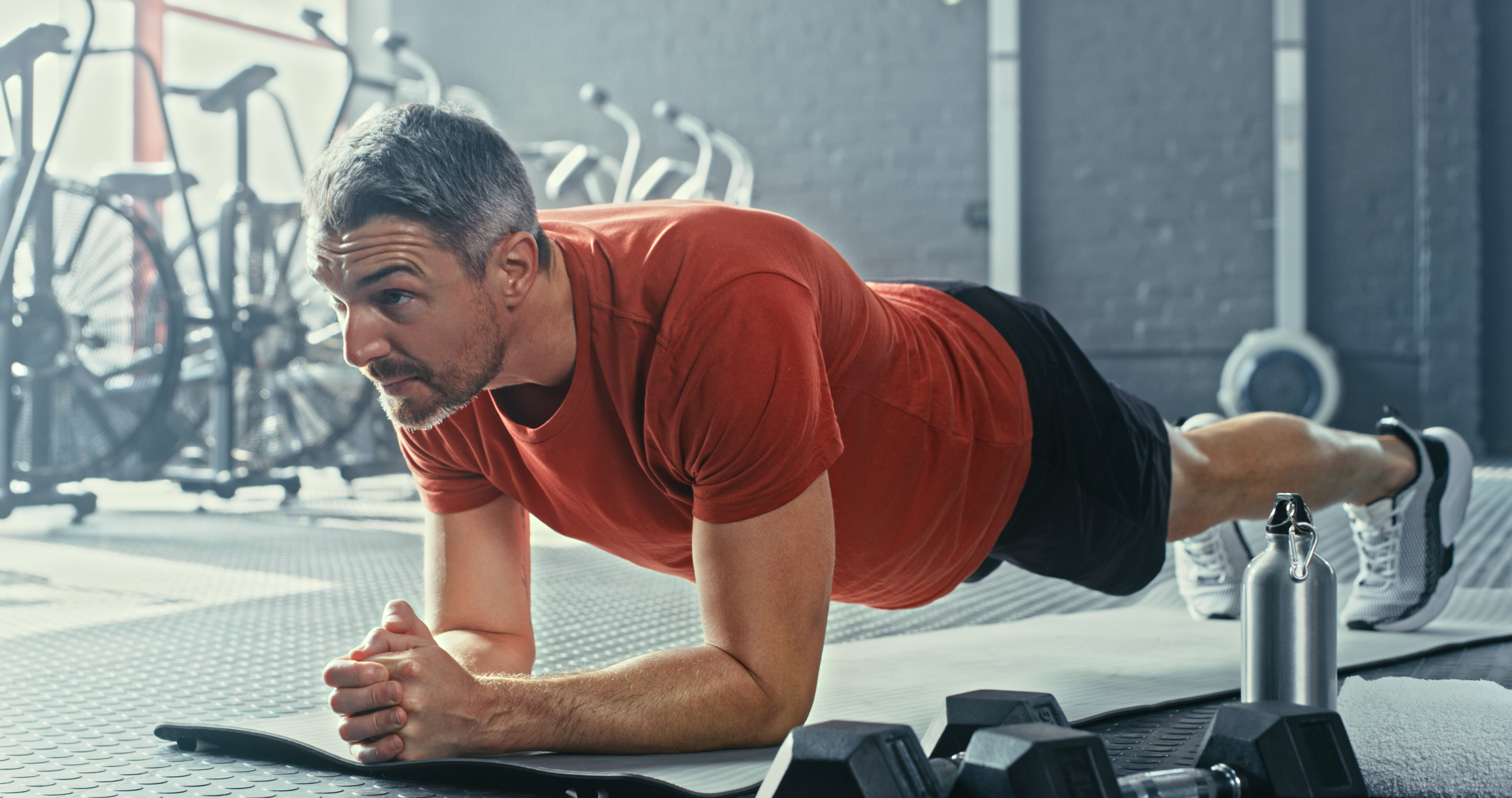 Man holding a plank position in a gym.
