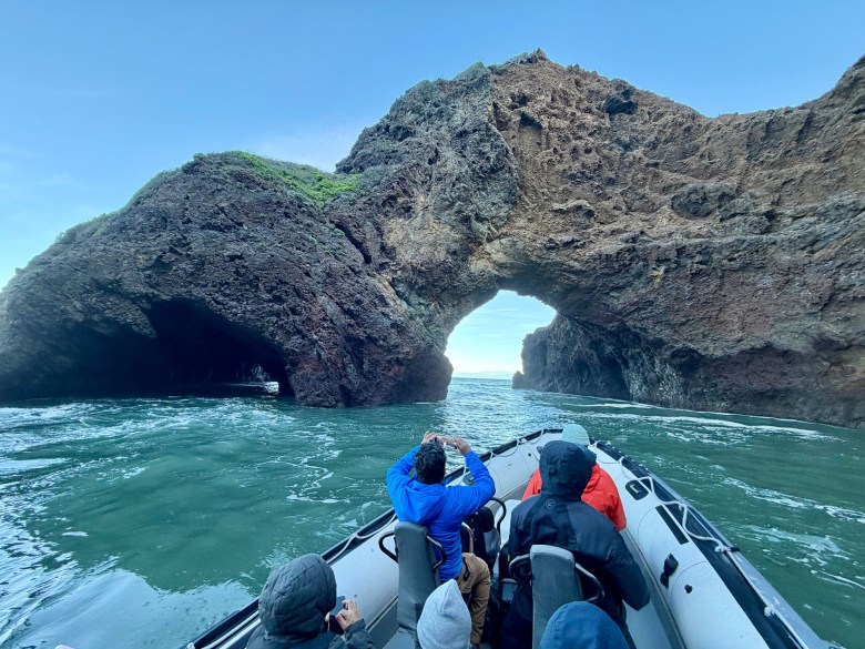A 30-foot zodiac operated by Pacific Offshore Expeditions approaches a sea arch during an orca quest in the Santa Barbara Channel.