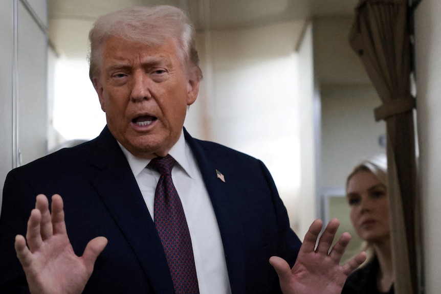 Trump waves his open hands as he speaks aboard a plane