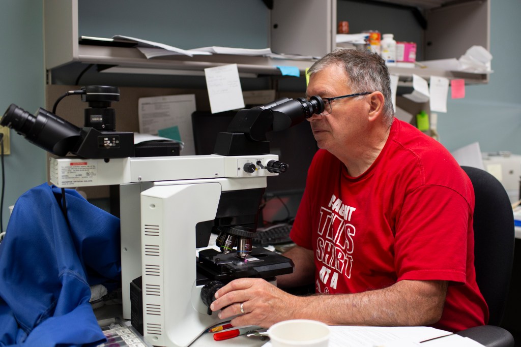 Kent County Medical Examiner, Dr. Stephen Cohle, is seen looking at slides under a microscope in his office on Thursday, September 11, 2026 in Grand Rapids, MI. 