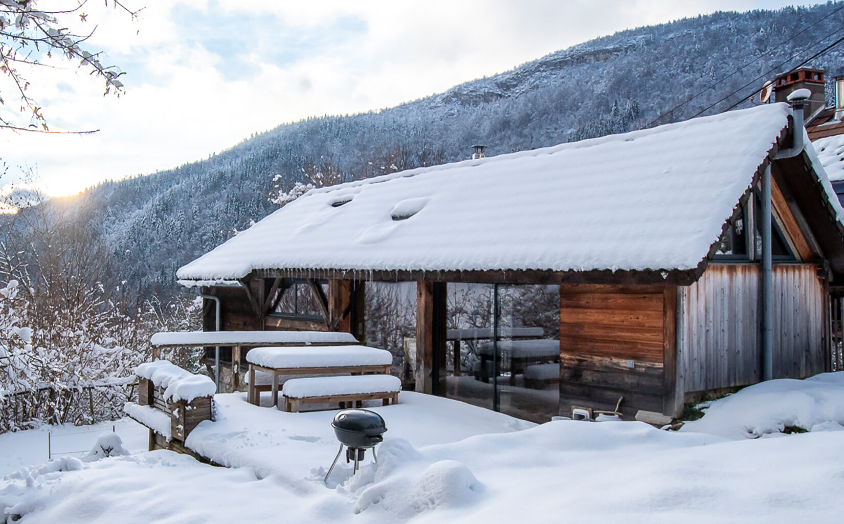 A restored alpine refuge overlooks Annecy from a wooded trailhead