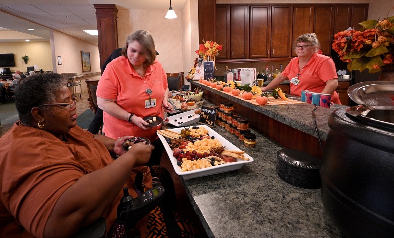Live Enrichment Associate for Dementia, Carrie Roper, helps resident Brenda fill a plate of snacks during Happy Hour at The Willows of East Lansing nursing home on Friday, Sept 19, 2925.  