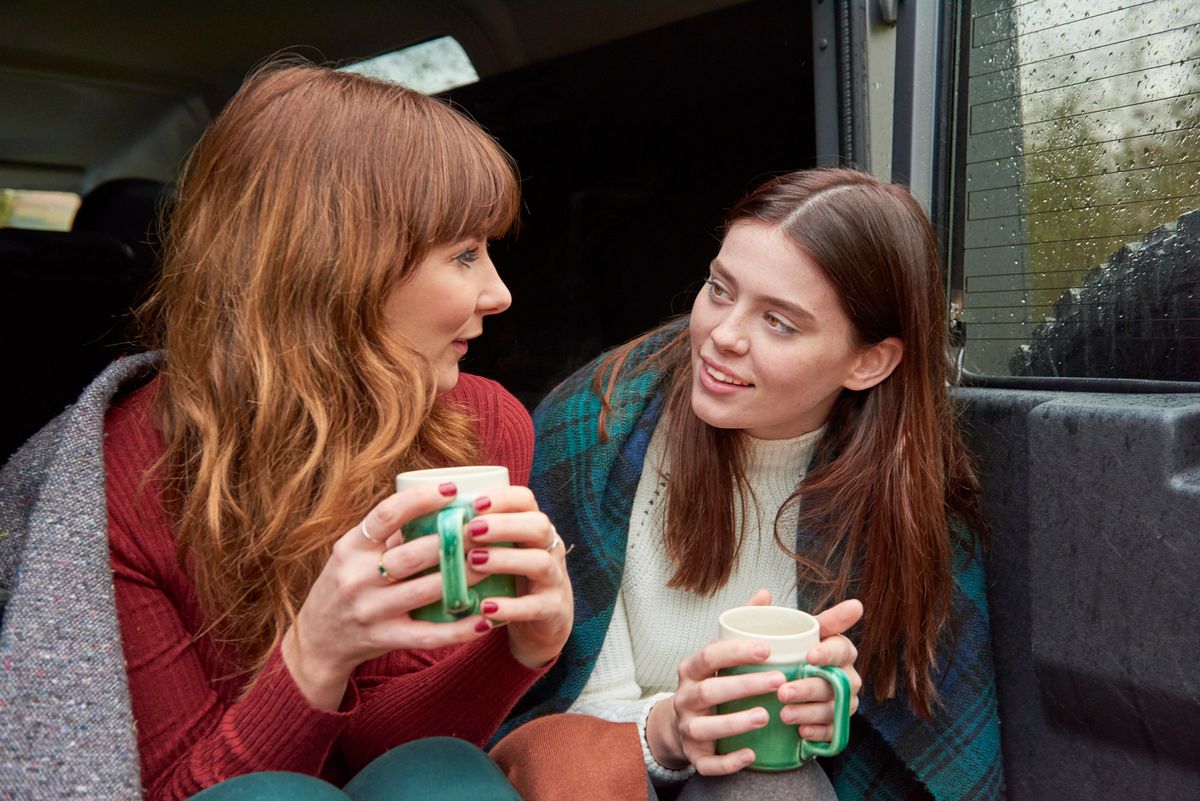 Friends sharing a hot drink in blankets