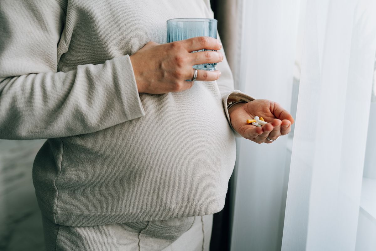 Pregnant woman holding medication and glass of water